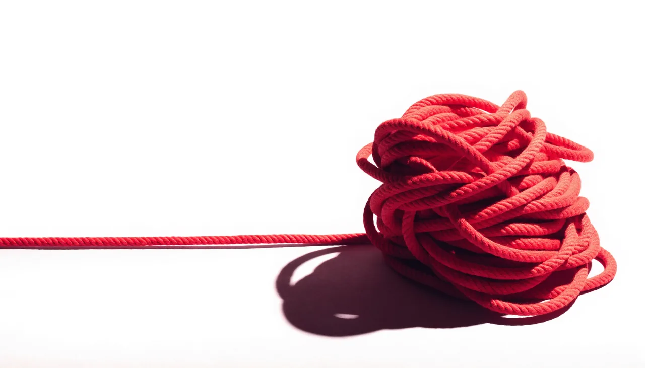 A conceptual still life showing a tangled line resolving into one clear signal.
